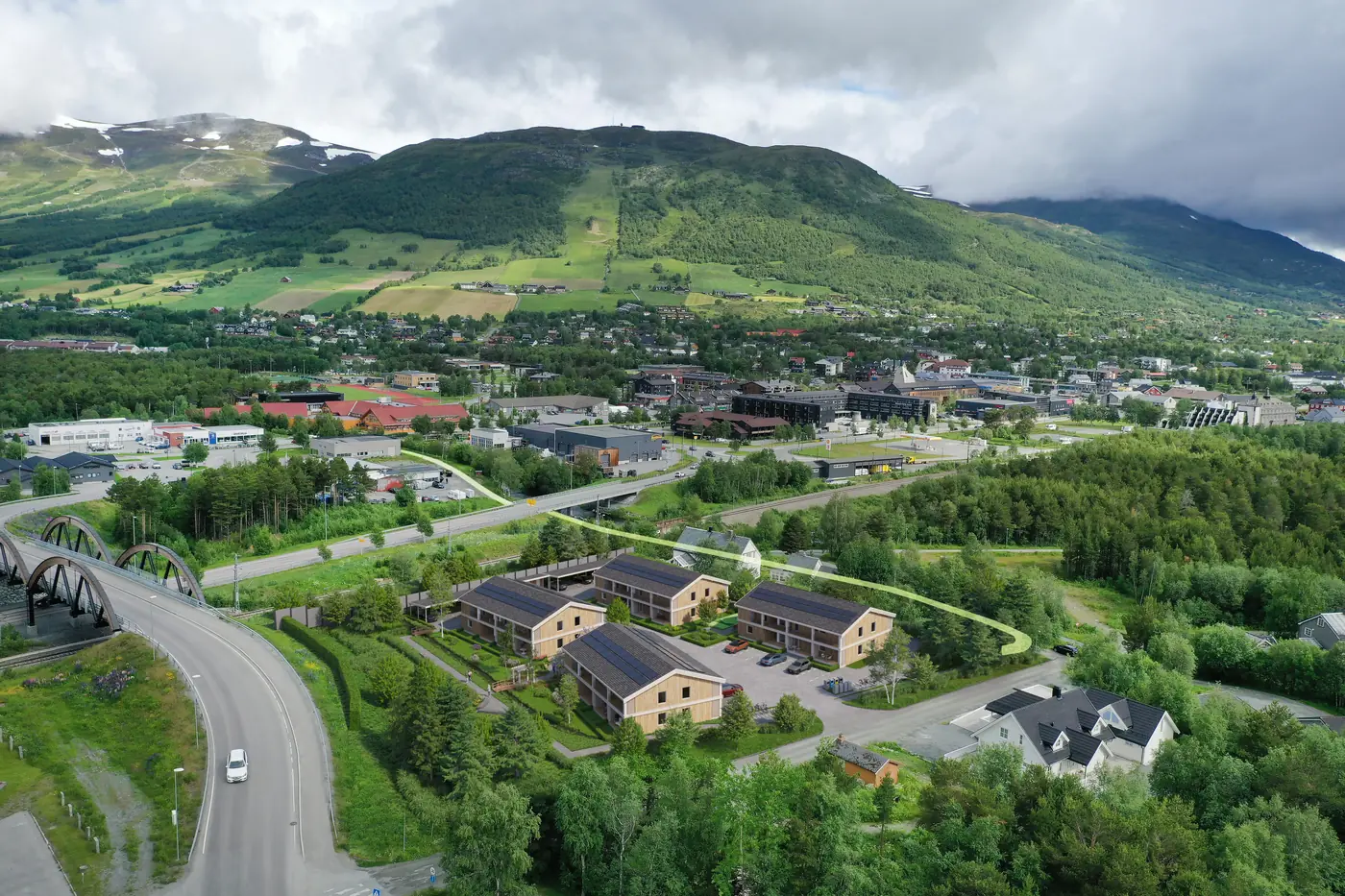 Fotomontasje av boligprosjekt med fire bygg og uteområder, sett fra luften mot fjellene
