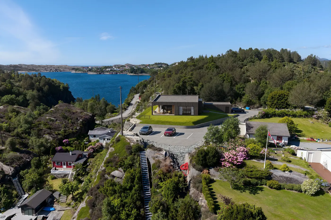 Fotomontasje av ny bolig på sjøtomt satt inn i dronefoto av kystlandskap